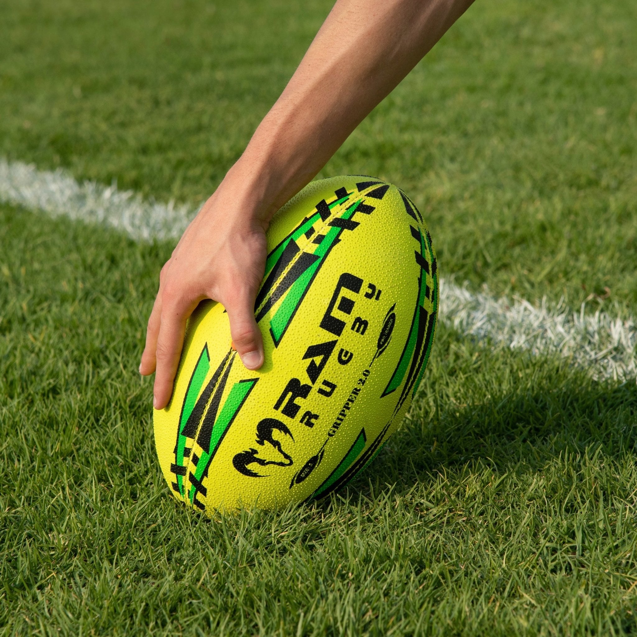 Stack of neon yellow, orange, and green Ram Rugby Gripper 2.0 Pro Trainer balls with two black breathable storage bags