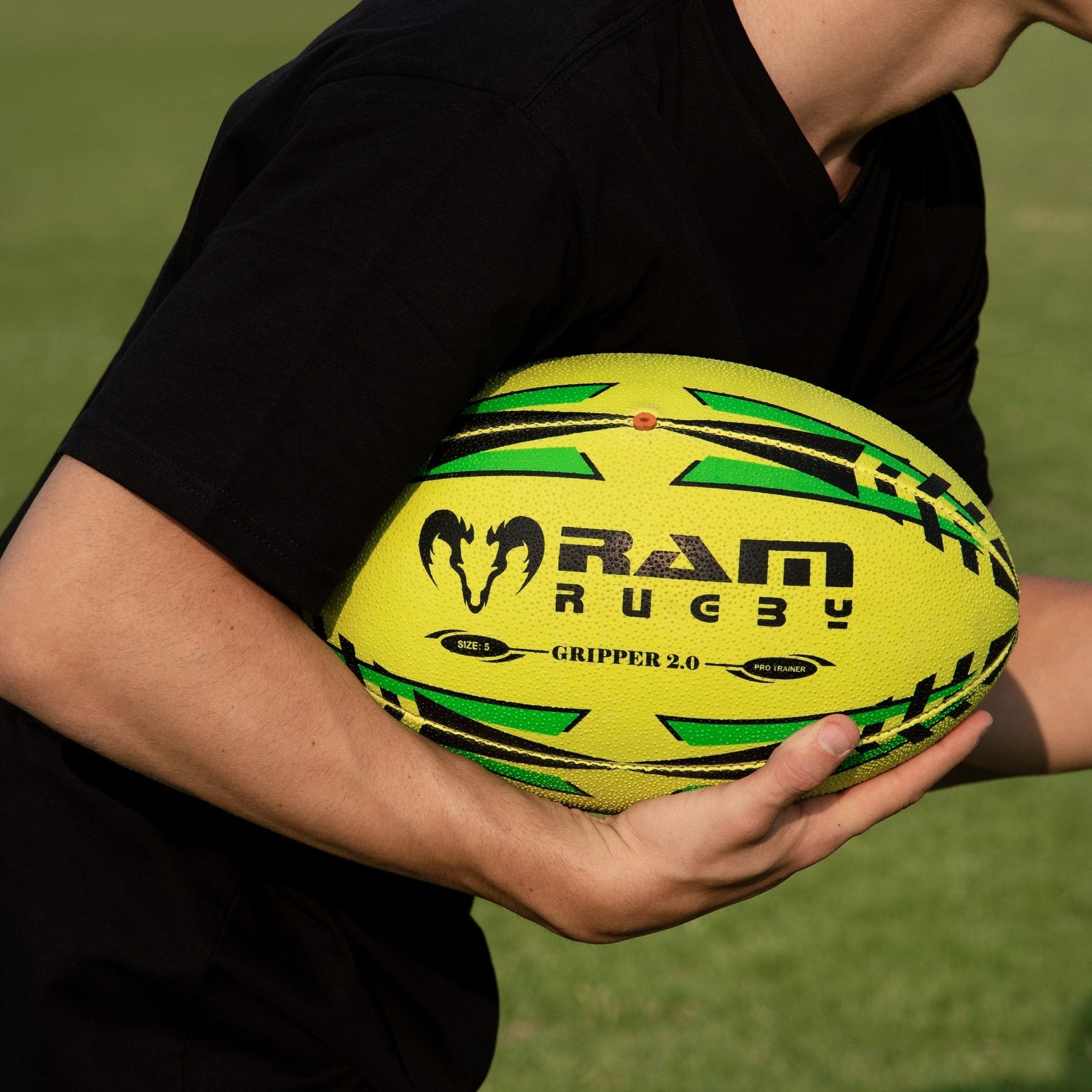 Stacked neon yellow, orange, and green Ram Rugby Gripper 2.0 Pro Trainer balls with two black breathable storage bags