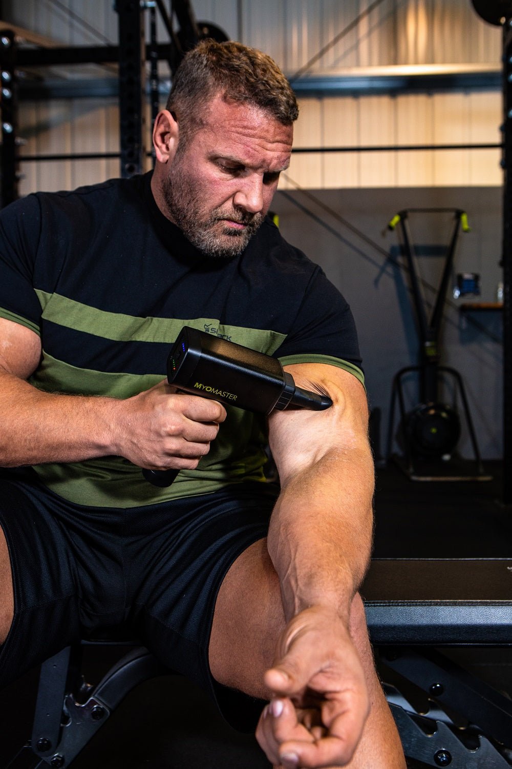 Power Plate MyoPro Massage Gun in black with ergonomic handle and multiple massage heads for muscle pain relief and recovery