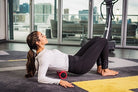 Power Plate DualSphere red massage tool resting on a wooden floor, showing its textured surface for muscle pain relief